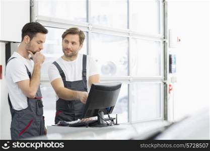 Male automobile mechanics conversing in repair shop