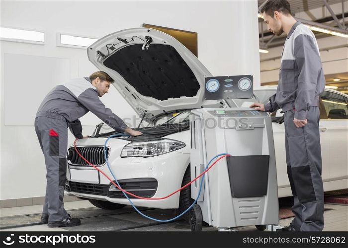 Male automobile mechanics examining car in repair shop