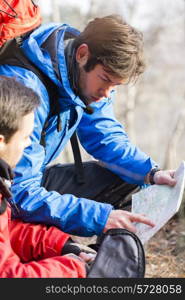 Male backpackers reading map in forest