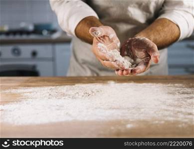 male baker dusted wooden table with wheat flour