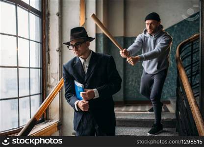 Male bandit with baseball bat attact his victim. Street hooligan commits a robbery attack on a man. Crime concept. Male bandit with baseball bat attact his victim
