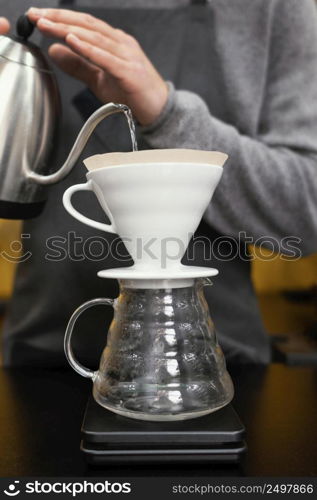 male barista pouring water coffee filter