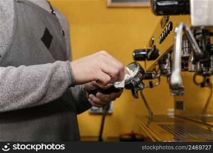 male barista with apron cleaning professional coffee machine