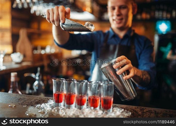 Male barman at the bar counter with glasses standing in ice. Bartender in pub. Barkeeper occupation. Barman at the counter with glasses standing in ice