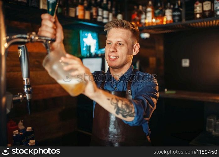 Male barman pouring beer at the bar counter. Barkeeper occupation, bartending. Male barman pouring beer at the bar counter