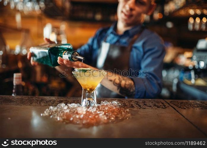 Male bartender pours beverage into the glass with ice. Barkeeper occupation, barman job. Bartender pours beverage into the glass with ice