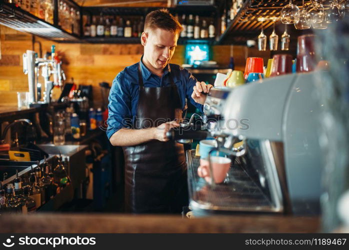 Male bartender prepares drink at the bar counter. Barkeeper occupation, barman working in pub. Male bartender prepares drink at the bar counter