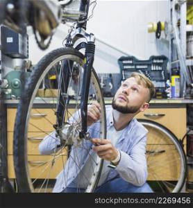 male bicycle mechanic repairing bicycle tire shop