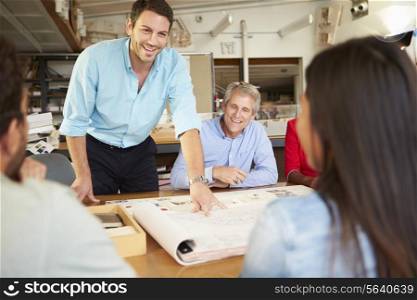 Male Boss Leading Meeting Of Architects Sitting At Table