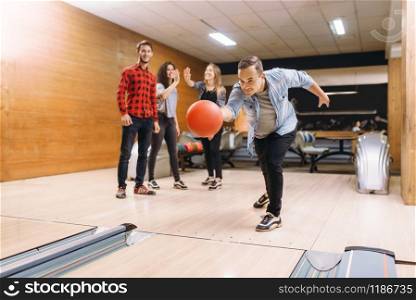 Male bowler throws ball on lane. Bowling alley teams playing the game in club, active leisure
