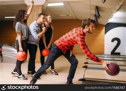 Male bowler throws ball on lane, front view, throwing in action. Bowling alley teams playing the game in club, active leisure. Male bowler throws ball, throwing in action