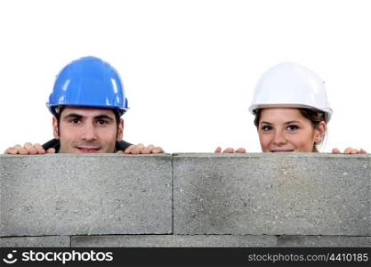 male bricklayer and female counterpart hiding behind wall