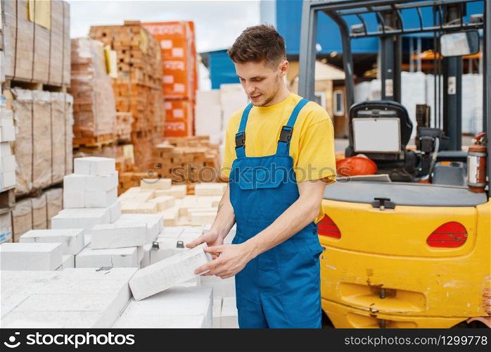 Male builder choosing bricks in hardware store. Constructor in uniform look at the goods in diy shop. Male builder choosing bricks in hardware store