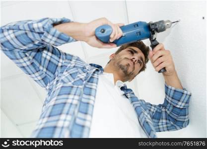 male builder drilling holes in wall at construction site