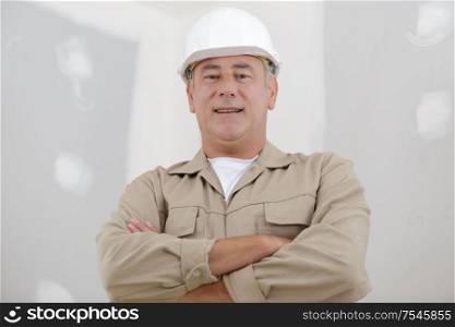 male builder in a helmet with crossed arms