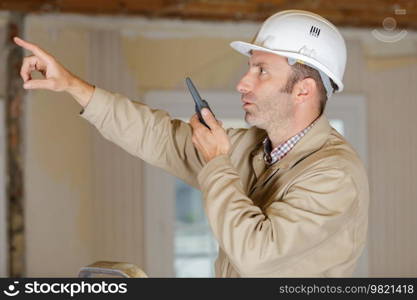 male builder in hardhat with walkie talkie