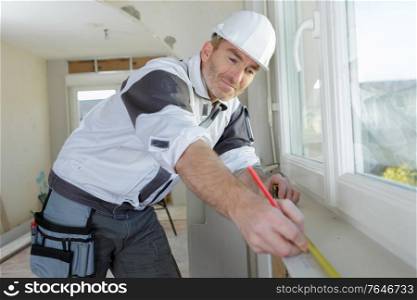 male builder making window measurements