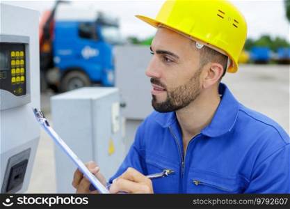 male builder or manual worker in helmet with clipboard