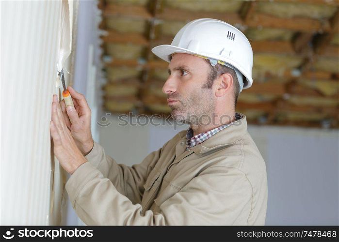 male builder removing old wallpaper