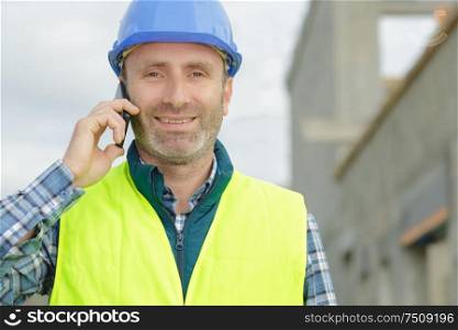 male builder talking on mobile phone outdoors