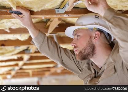 male builder working on ceiling joists