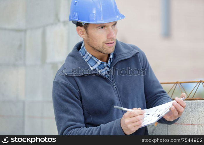 male builder writing on clipboard