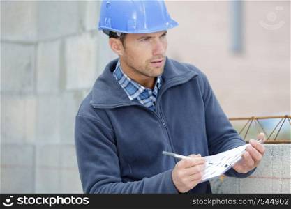 male builder writing on clipboard
