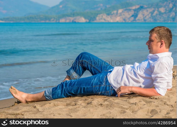 male businessman lying on the beach near the sea