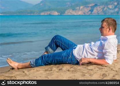 male businessman lying on the beach near the sea