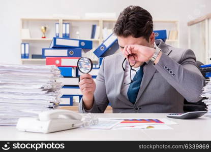 Male businessman with magnifying glass in office