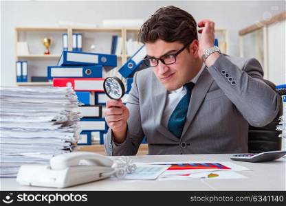 Male businessman with magnifying glass in office