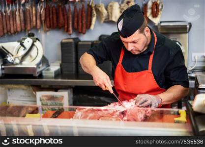 Male butcher boning fresh ham in a modern butcher shop with metal safety mesh glove. Butcher boning fresh ham in a modern butcher shop