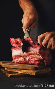 Male butcher cuts raw beef meat