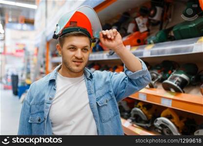 Male buyer trying on a mask in hardware store. Customer look at the goods in diy shop, shopping in building supermarket