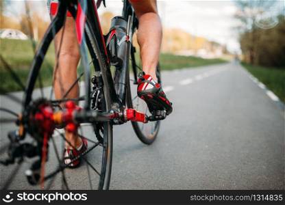 Male bycyclist rides on bike path, view from the rear wheel. Cycling on asphalt road. Sportsman rides on bicycle