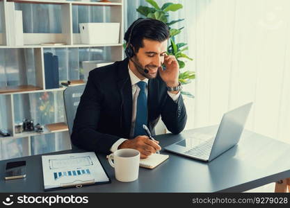 Male call center operator or telesales representative siting at his office desk wearing headset and engaged in conversation with client providing customer service support or making a sale. fervent. Male call center operator or telesales agent working on his desk. fervent