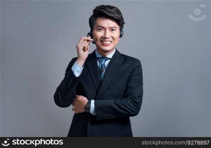 Male call center operator wearing headset and formal suit standing confidently with gesture for product advertisement or HR recruitment on isolated background. Jubilant. Male call center operator wearing headset making advertising gesture. Jubilant