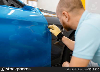 Male car wrapper hands installs protective vinyl foil or film on vehicle door. Worker makes auto detailing. Automobile paint protection, professional tuning. Car wrapper hands installs vinyl foil or film