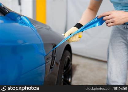 Male car wrapper hands installs protective vinyl foil or film on vehicle door. Worker makes auto detailing. Automobile paint protection, professional tuning. Car wrapper hands installs vinyl foil or film