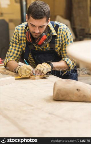 male carpenter measuring wooden block with ruler pencil