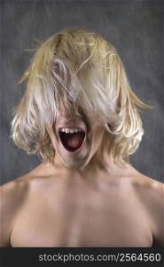 Male Caucasian teen with hair over face screaming.