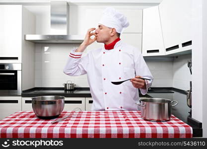 Male chef at kitchen tasting the dish