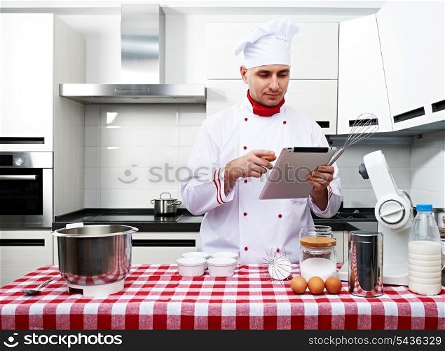 Male chef at kitchen with tablet pc getting ready to cook