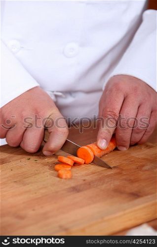 Male chef chopping carrot