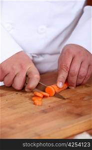 Male chef chopping carrot