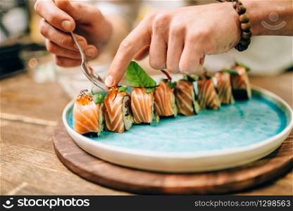 Male chef cooking sushi rolls, japanese food preparation process. Traditional asian cuisine, seafood delicious. Male chef cooking sushi rolls, japanese food