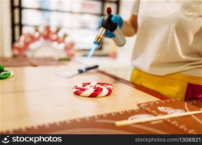 Male chef hands in gloves, melt caramel with a gas burner. Candy preparation in pastry shop. Sugar dessert cooking. Chef melt caramel with a gas burner