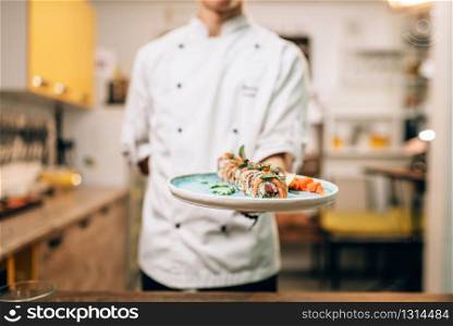 Male chef hold sushi rolls on plate, japanese cuisine preparation process. Traditional asian food, seafood delicious