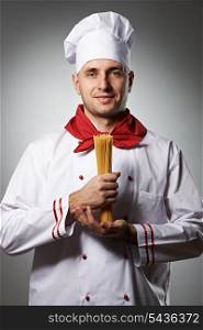 Male chef holding pasta against grey background