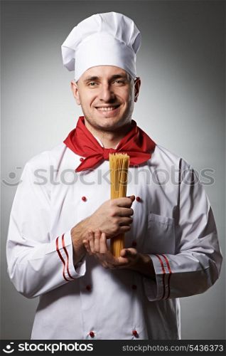 Male chef holding pasta against grey background